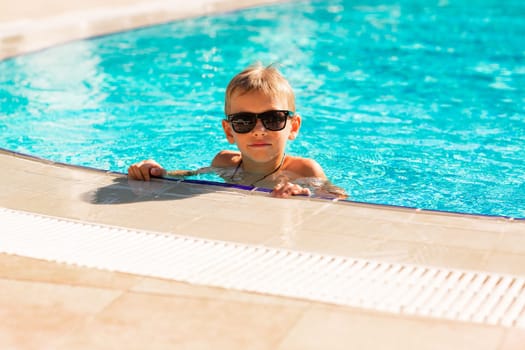 Happy little boy having fun at the pool at the resort. Summer holiday for kids concept