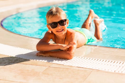 Happy little boy having fun at the pool at the resort. Summer holiday for kids concept