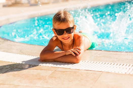 Happy little boy having fun at the pool at the resort. Summer holiday for kids concept