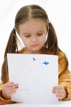 A preschooler girl is looking at a drawing she has drawn.