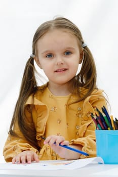 Happy european kid girl draws painting with colored pencil.