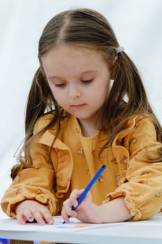 Portrait of a сute european kid girl painting with colored pencil.