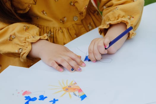 European kid girl painting with colored pencil. Kindergarten children education concept. Close-up of children's drawing.