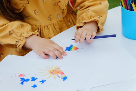 European kid girl painting with colored pencil. Kindergarten children education concept. Close-up of children's drawing.