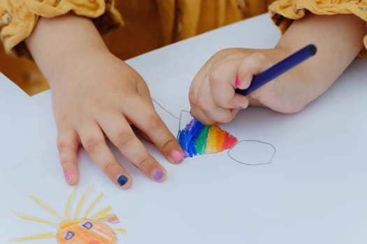 European kid girl painting with colored pencil. Kindergarten children education concept. Close-up of children's drawing.