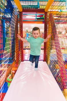 little boy playing inside a tunnel in the playground voting balls.