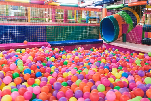 Indoor children's playground in the amusement park with colored balls to play / Inside the beautiful children's playground colored plastic ball of the game room.