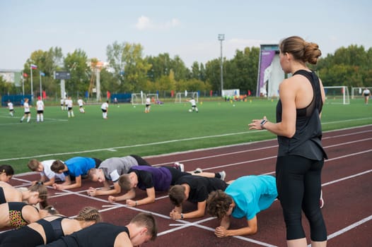 Female coach and group of children conducts a training session at the stadium. School gym trainings or athletics