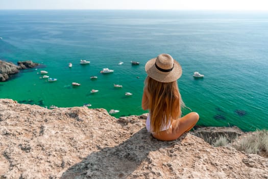 Woman travel sea. Happy woman in a beautiful location poses on a cliff high above the sea, with emerald waters and yachts in the background, while sharing her travel experiences.