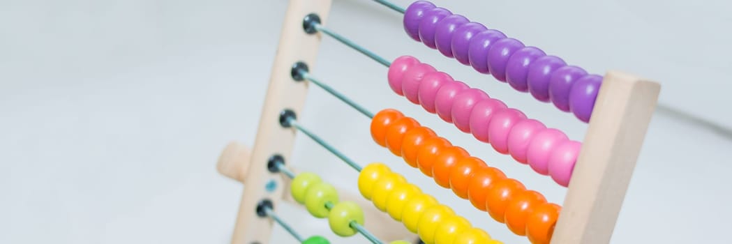 Preschooler baby learns to count. Cute child playing with abacus toy. Little boy having fun indoors at home, kindergarten or day care centre. Educational concept for preschool kids.