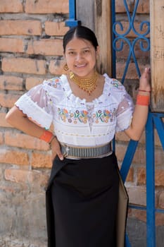 young feminist indigenous woman in traditional otavalo dress looking at the camera smiling and leaning on an iron gate. High quality photo