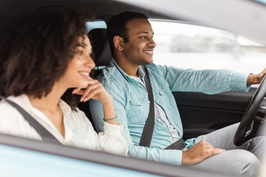 Romantic Getaway. Cheerful arabic couple driving sharing experiences of road adventure together, sitting on front seats in car. Vehicle ownership concept. Side view, selective focus