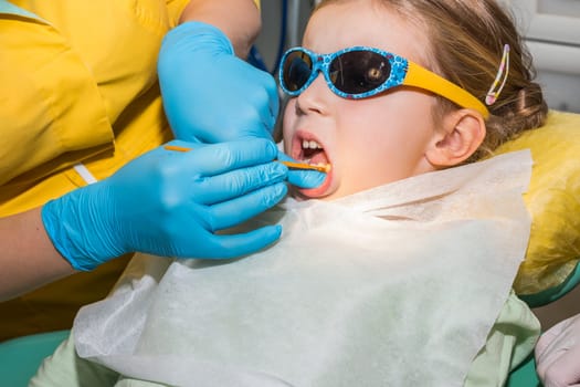 Close up in child mount and checking tooth and by dental mirror tools.