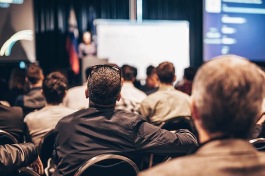 Speaker giving a talk in conference hall at business event. Rear view of unrecognizable people in audience at the conference hall. Business and entrepreneurship concept