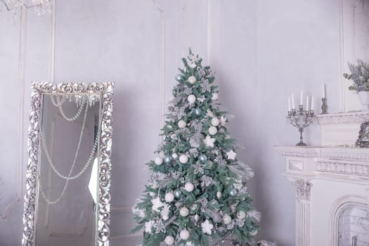 Christmas holiday background. Christmas tree with silver and white decoration. Beautiful Christmas tree closeup decorated with ball, holly berry, tinsel, pastel colors.