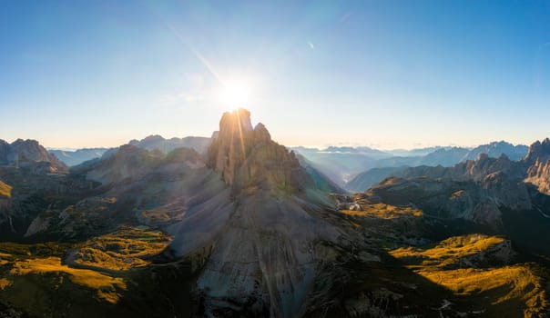 Mountain landscape of Tre Cime di Lavaredo at sunrise. Rocky ranges and wide highland valleys in Alps under clear sky aerial view in back lit