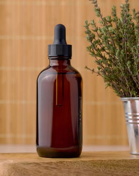 Thyme essential oil in glass bottle with dropper and fresh thyme sprigs on table, cosmetic ingredient