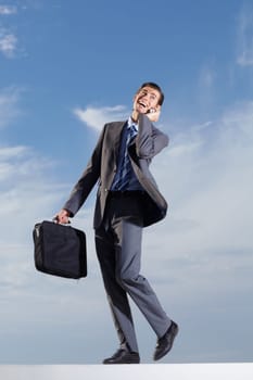 Happy business man, phone call and sky with briefcase for mobile contact, communication and corporate connection. Male employee walking by clouds, talking on smartphone and mockup networking with bag.