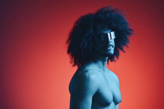 Portrait of fashion man with curly hair on red background with stylish glasses, multinational, colored light, black leather jacket trend, modern concept, sexy body. High quality photo