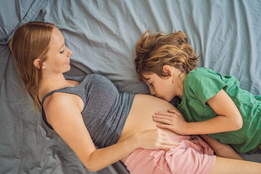 Young beautiful pregnant woman and eldest son. The cute boy leaned his ear against his mother's belly. Expecting a baby in the family concept. Preparing an older child for a younger one.