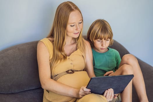 pregnant mom and son look at the tablet. Reading a book or watching a cartoon or making a video call. Look at the photo from the ultrasound.