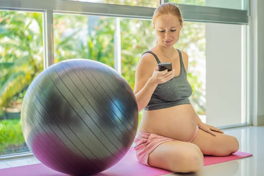 Beautiful pregnant woman texting on smartphone during sports training.