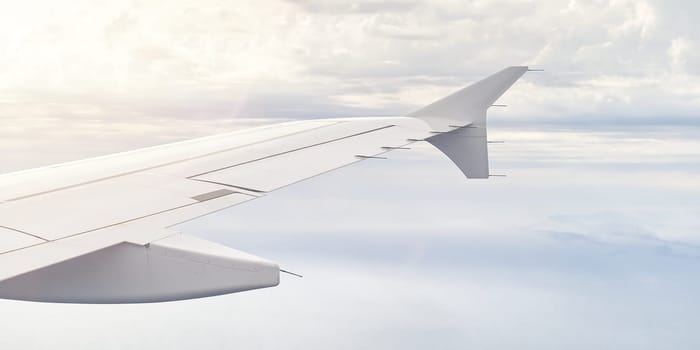 Airplain wing view thrue window in the sky. Clouds and sky as seen through porthole of an aircraft with airplane's wing