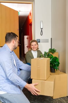 Happy couple moving in their new apartment carrying cardboard boxes. Young couple moving in new home. fun with cardboard boxes at moving day.