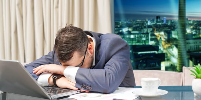 Tired man working at home office, Exhausted, stressed, overworked man, financial market decline, unsuccessful investments. tension headache. Sad businessman lying on laptop.