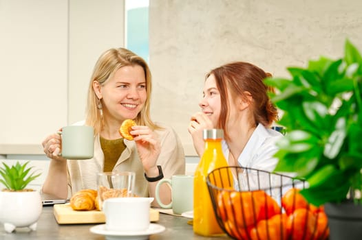 Happy mother and daughter having breakfast in kitchen and using digital devices. Lifestyle, Morning breakfast, mother and daughter together.