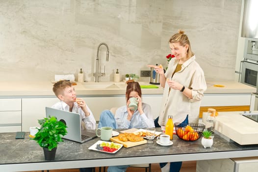 Young family with school kids have fun at breakfast time. Happy family eating healthy breakfast. Quality time with Family in kitchen eating together. Family Using Digital Devices At Breakfast