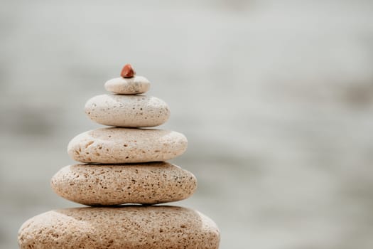 Pyramid stones on the seashore with warm sunset on the sea background. Happy holidays. Pebble beach, calm sea, travel destination. Concept of happy vacation on the sea, meditation, spa, calmness.