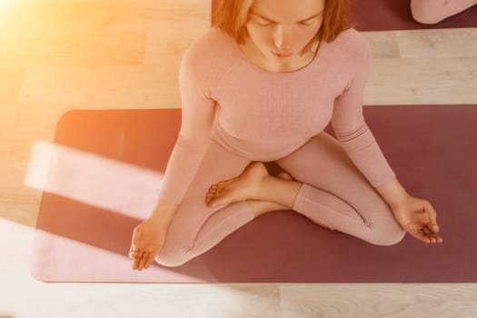 Young woman with long hair in white swimsuit and boho style braclets practicing outdoors on yoga mat by the sea on a sunset. Women's yoga fitness routine. Healthy lifestyle, harmony and meditation