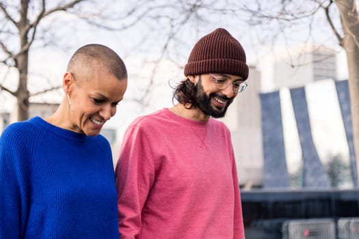 couple of bearded man and shaved head woman smiling happy walking in the city, concept of love and modern lifestyle