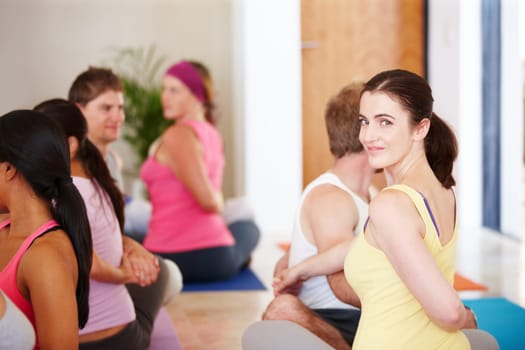 Enjoying a yoga class. Portrait of a happy woman sitting and doing stretches during a yoga class