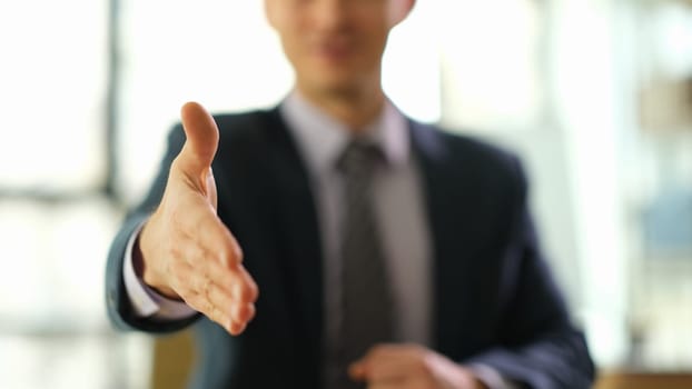 Businessman in suit extending his hand for handshake or greeting closeup. Business cooperation concept