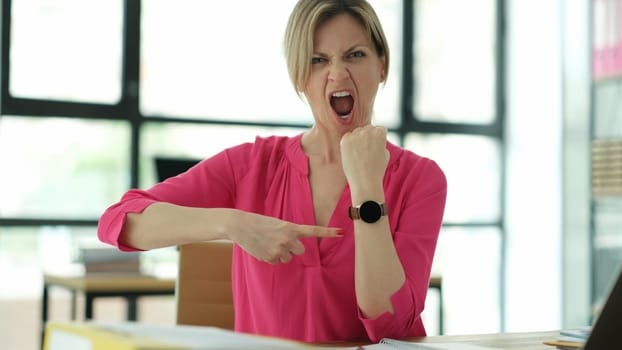 Woman manager screaming and pointing finger at wrist watch in office. Time management and being late at work concept