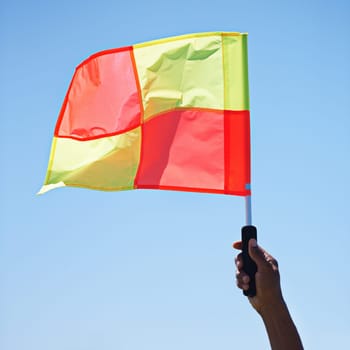 Flag, stop and soccer referee in football match or game wave a foul sign during sport training or workout. Hand, sports and person or assistant official raise or signal mistake in sky background.