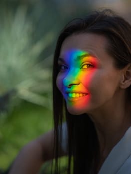 Portrait of caucasian woman with rainbow beam on her face outdoors