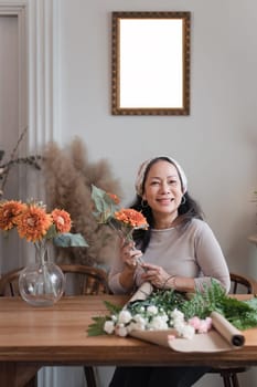 Startup, small business, flower shop. Older florist putting a flower on a vase.