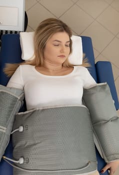 Top view pressure therapy procedure. Woman lying in massaging suit in hospital, treatment of varicose veins, edema, lymphatic drainage, weight loss. Relaxation,cure. Pressotherapy concept. Vertical
