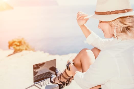 Happy girl doing yoga with laptop working at the beach. beautiful and calm business woman sitting with a laptop in a summer cafe in the lotus position meditating and relaxing. freelance girl remote work beach paradise