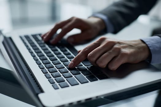 man's hands typing on laptop keyboard in interior