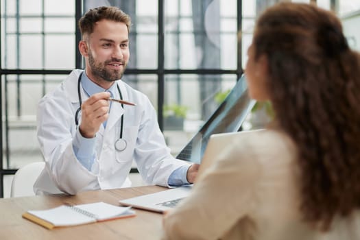 Young serious competent male doctor looking at X-ray at doctor's office