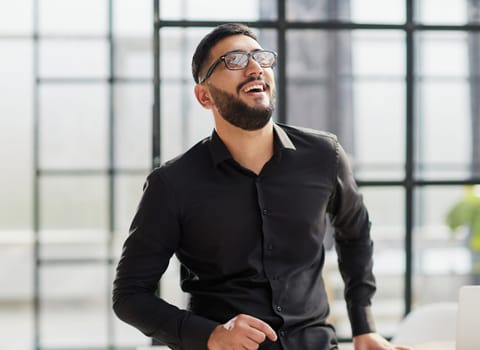 young businessman smiling in the office with his arms crossed