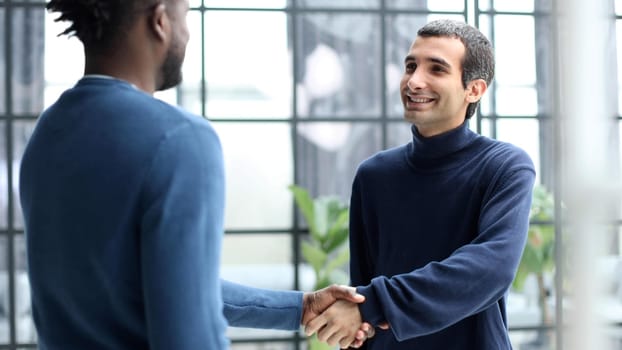 Diverse male colleagues in modern office corridor, young african american and caucasian business people discussing common project work, meeting in company work