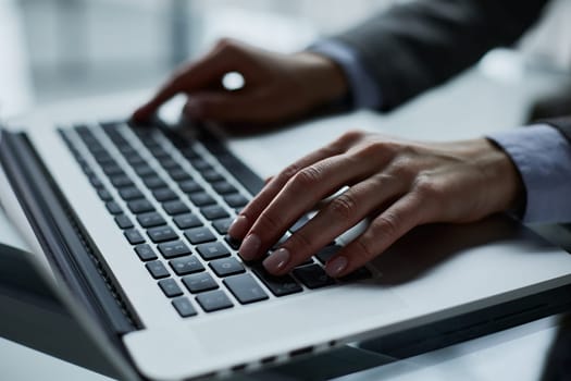 man's hands typing on laptop keyboard in interior