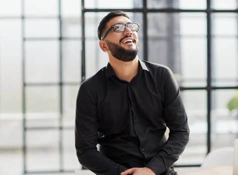 young businessman smiling in the office with his arms crossed