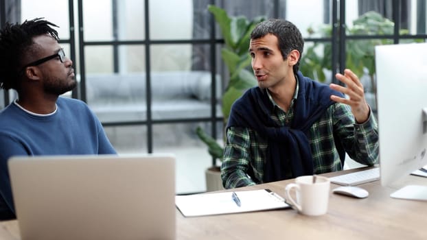 Business people working together in a modern trendy office behind a laptop