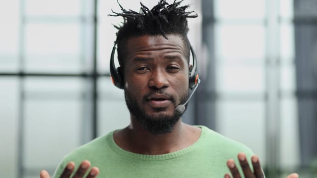 Operator of hot line. Portrait of cheerful african customer service representative with headset in call center, empty space
